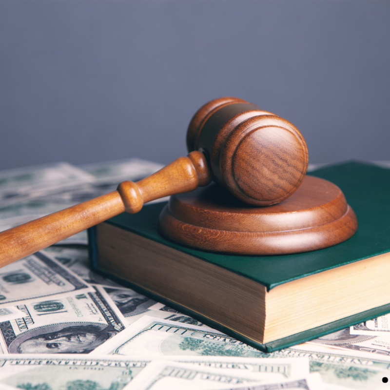 Maillet de juge sur un livre de loi et des billets d’argent.